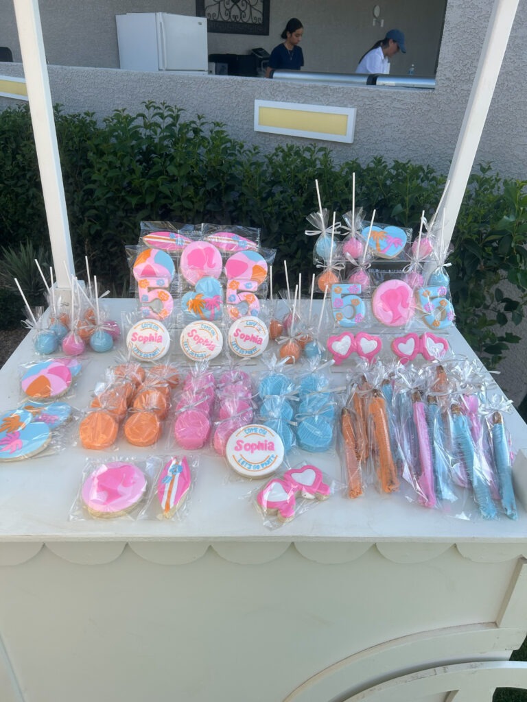 Colorful, themed treats displayed on a table featuring cookies and lollipops for a celebration, personalized with the name "Sophia."