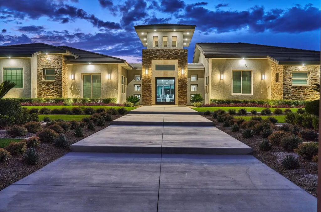Modern residential building with stone accents, landscaped path, and vibrant sunset sky. Showcases architectural design and curb appeal.