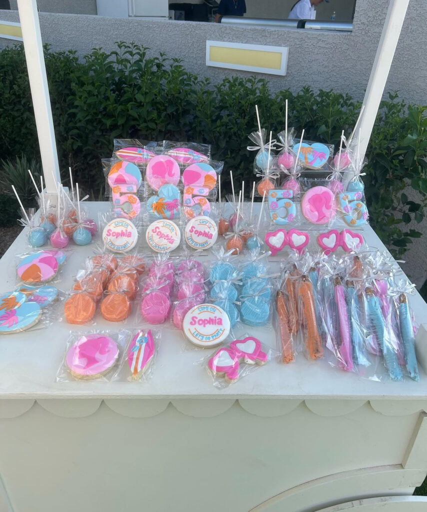 A colorful display of cookies, cake pops, and candies, decorated for a celebration, featuring pastel shades and personalized with the name "Sophia."